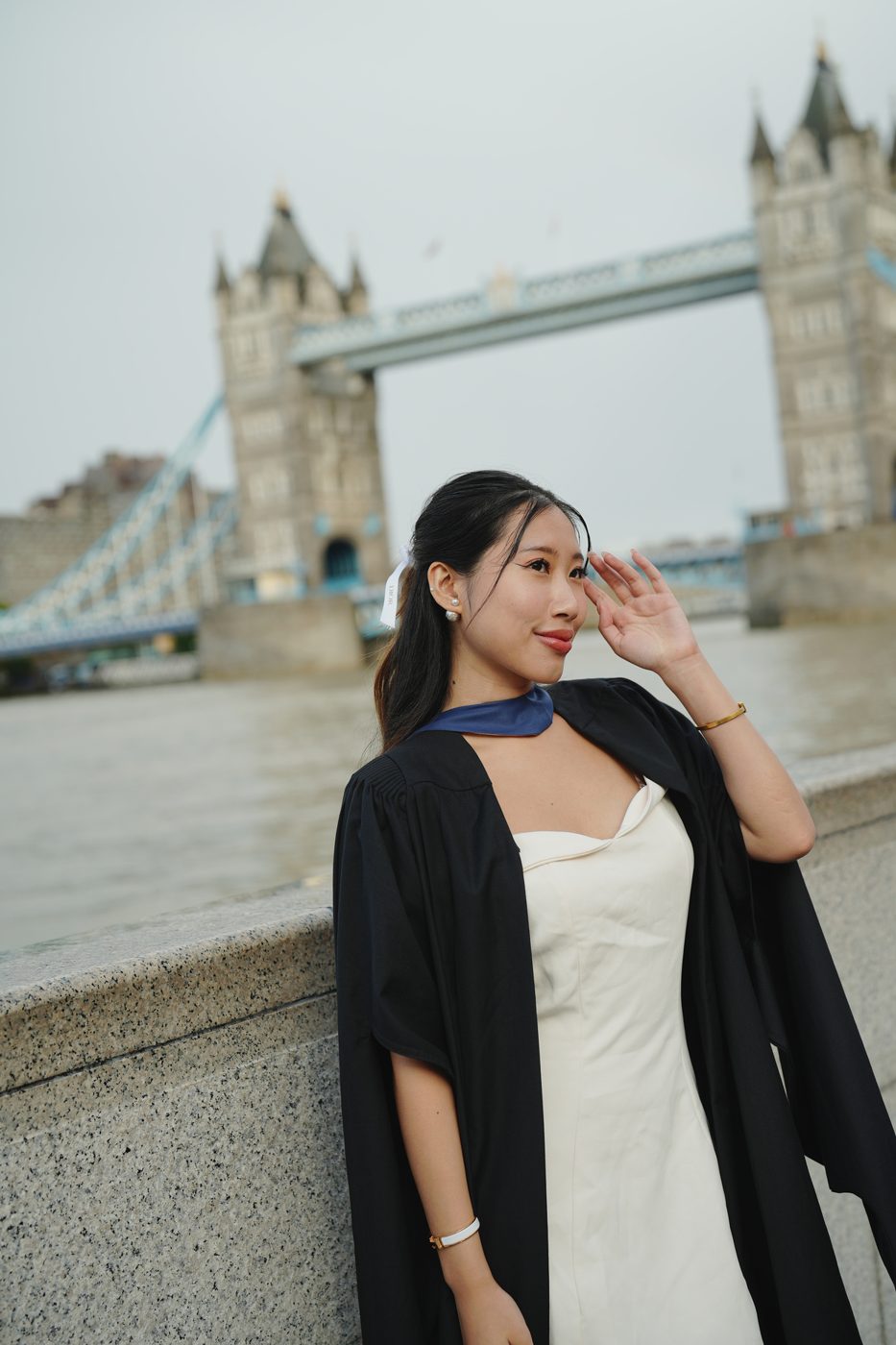 Boonyita in her graduation gown beside Tower Bridge, London